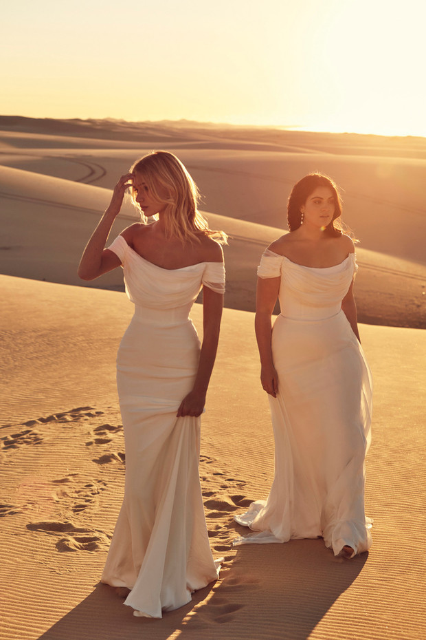 Two women in elegant white dresses on a desert landscape