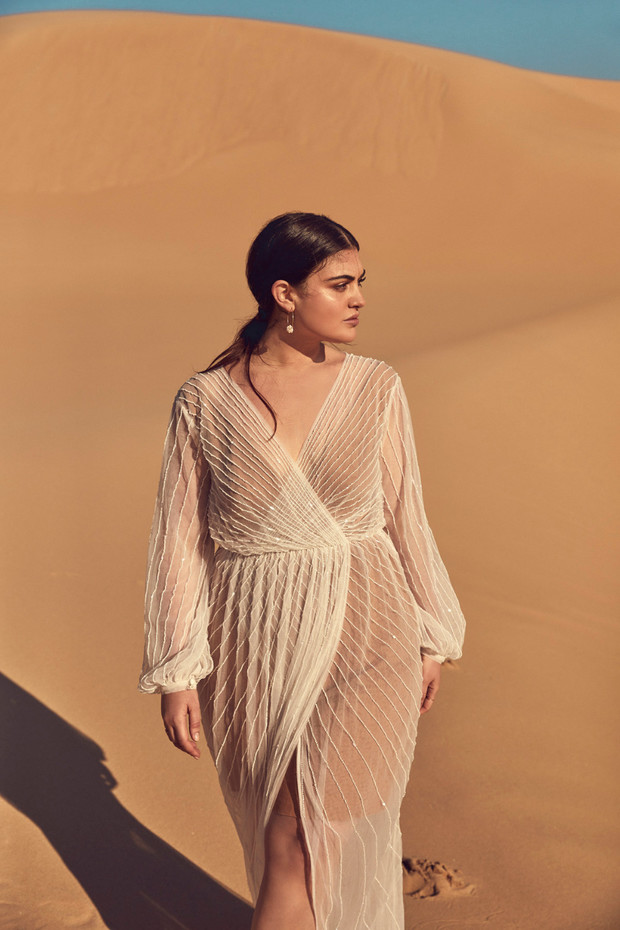 Woman in elegant sheer dress posing in the desert dunes