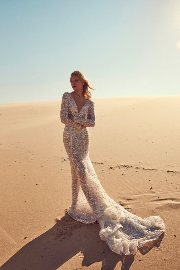 Bride in sparkly wedding dress standing on the sand