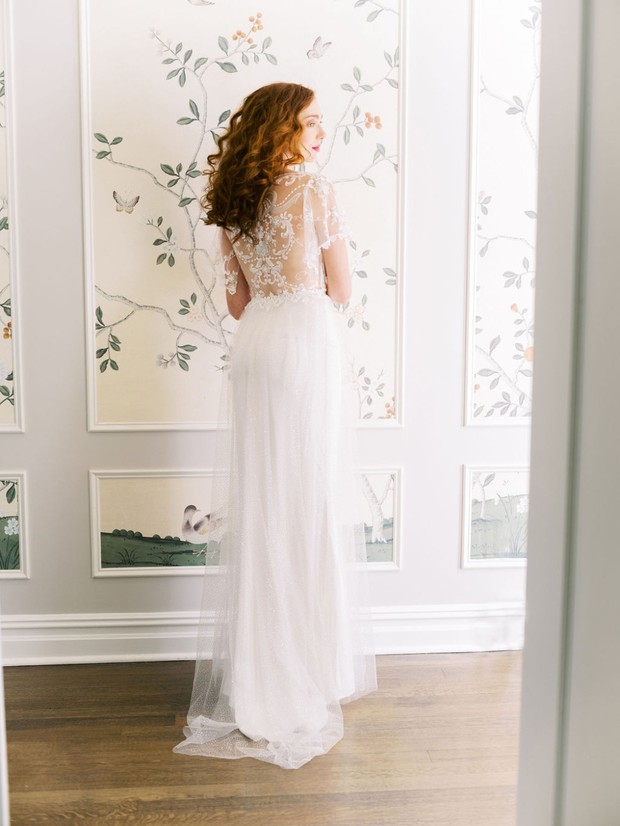 Red haired bride in sheer wedding dress poses indoors