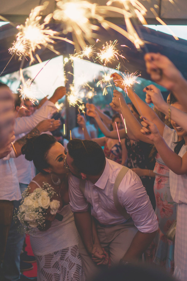 Newlyweds share a kiss under a shower of sparklers at wedding