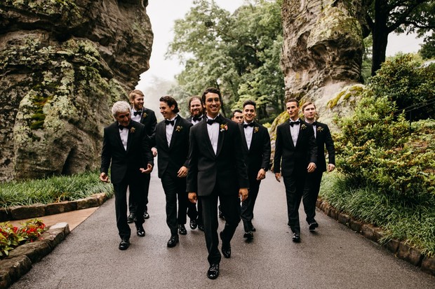 Groomsmen walk together on a path towards the camera in nature