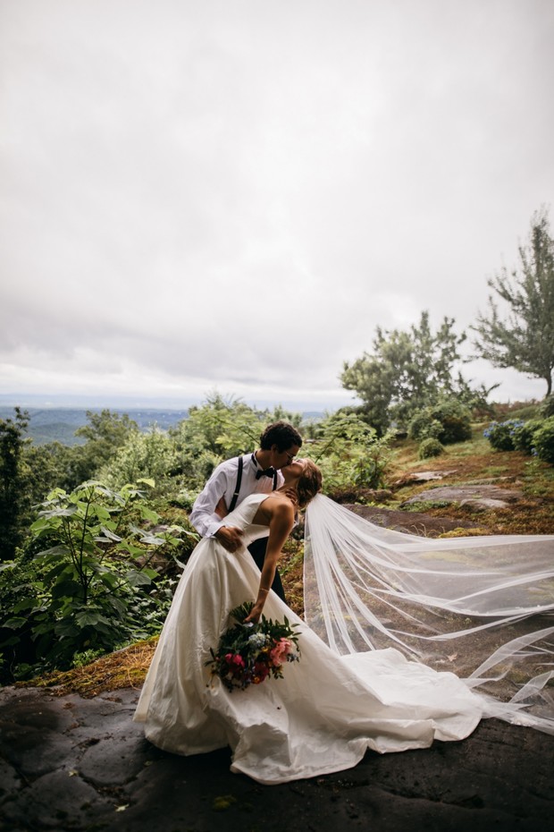 Romantic wedding couple kissing on a cloudy mountain top
