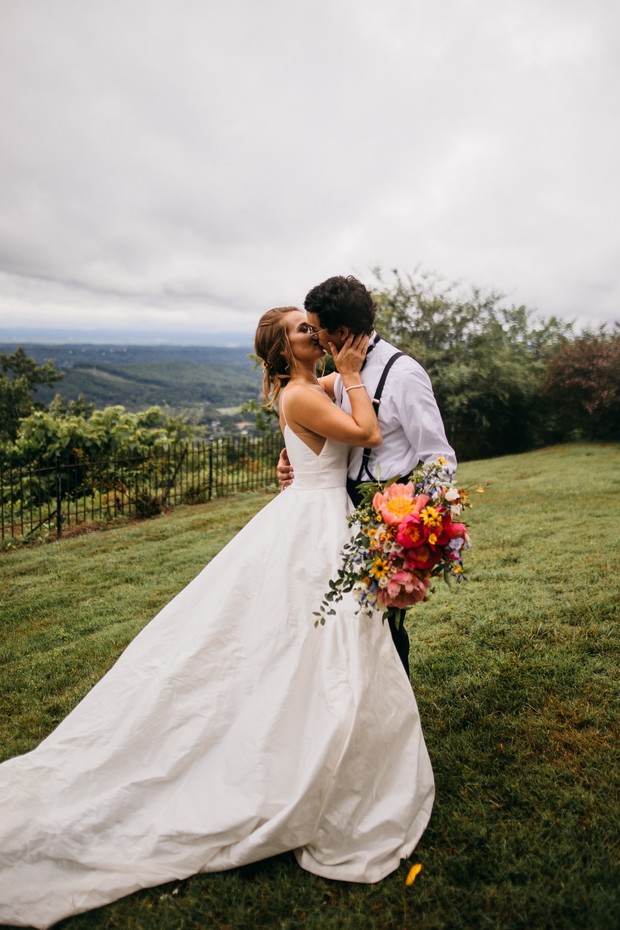 Bride and groom share a kiss on their wedding day with a bouquet