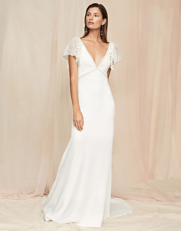 Elegant bride in a flowing white wedding dress with lace sleeves