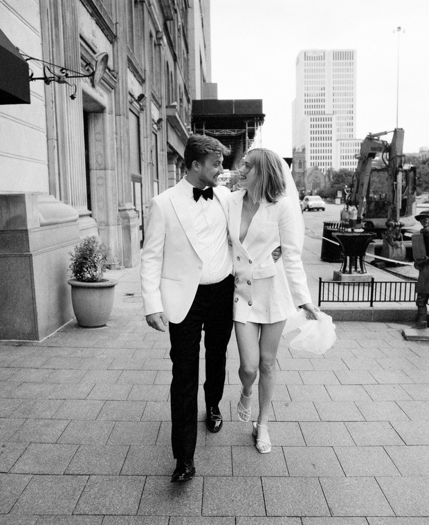 Newlywed couple strolling happily on a city sidewalk, in grayscale