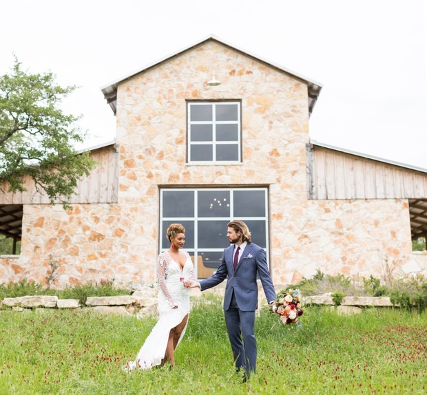 Elegant wedding couple walking in front of a stone barn