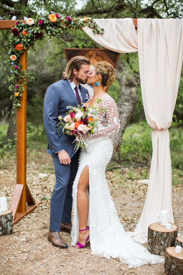 Wedding couple kissing at outdoor ceremony with floral archway