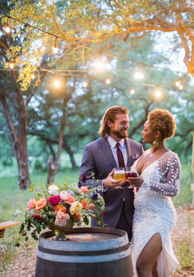 Wedding couple toasting drinks with flowers on a barrel
