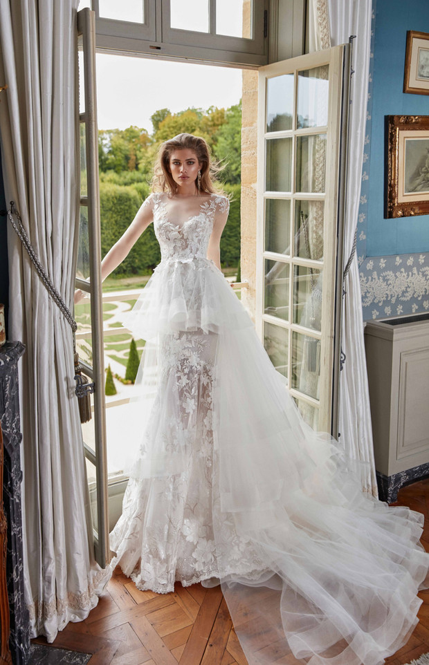Elegant bride in a lace wedding dress, standing by a window