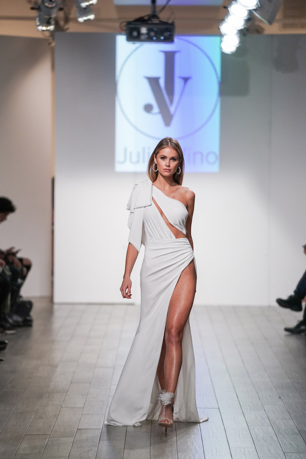 Model in white gown walking on a runway at a fashion show
