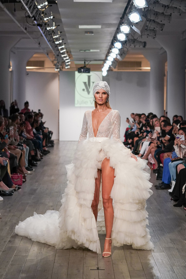 Elegant bride in a dramatic ruffled wedding gown walks the runway