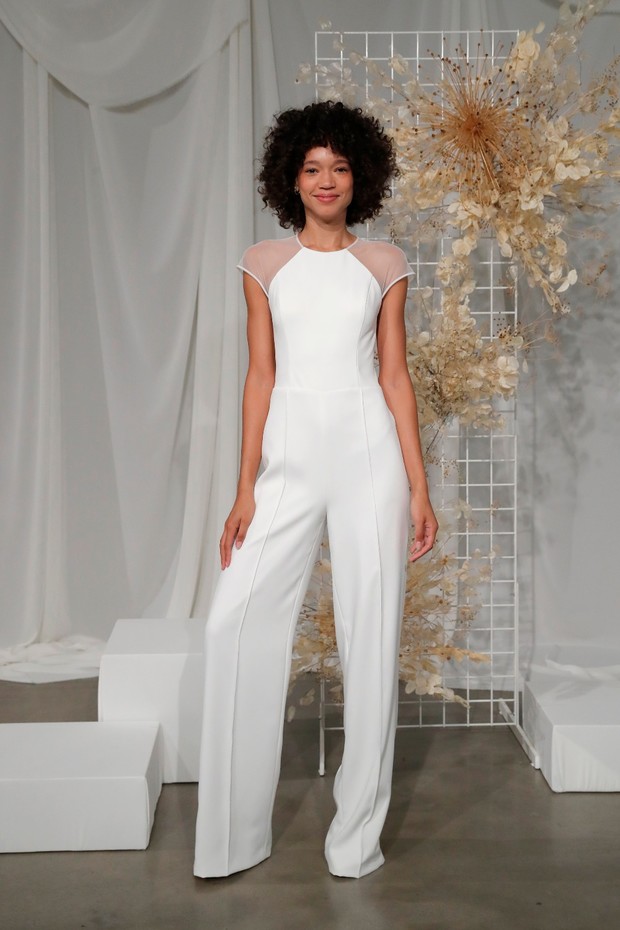 Woman in stylish white wedding jumpsuit with sheer sleeves