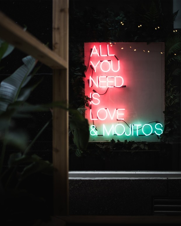 Neon sign saying All you need is Love and Mojitos, at night