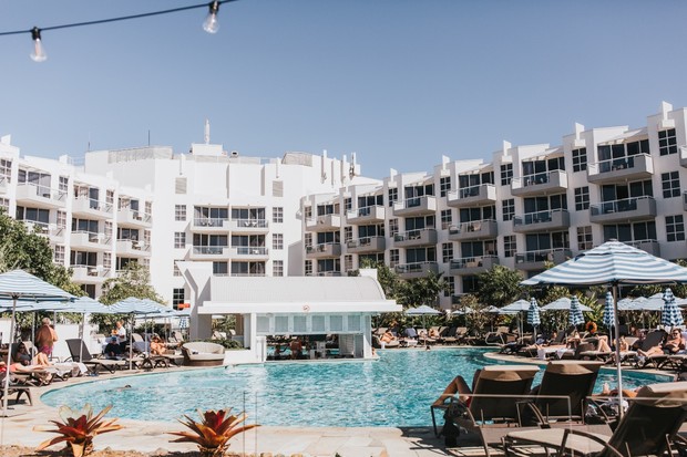 Luxury resort pool scene with white buildings and umbrellas