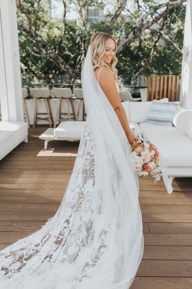 Smiling bride in a beautiful white wedding dress holding flowers