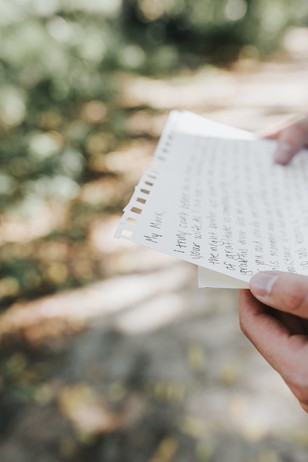 Person holding a letter outdoors with blurred green background