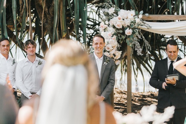 Groom smiles awaiting his bride at a beautiful beach wedding ceremony