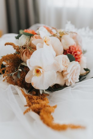 Elegant wedding bouquet with orchids and roses on a white veil