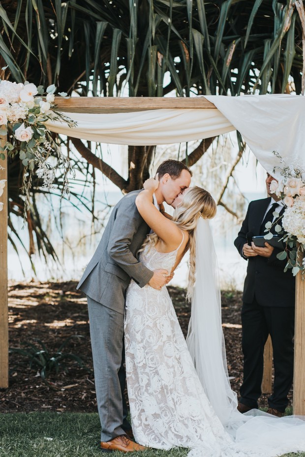 Bride and groom share a kiss at outdoor wedding ceremony