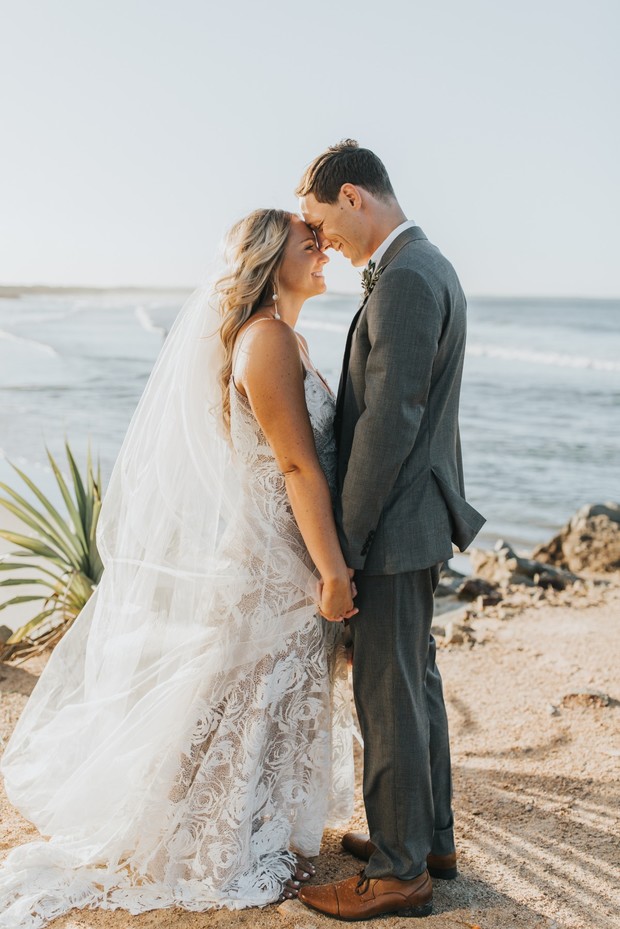 Happy couple holding hands, embracing each other at the beach wedding