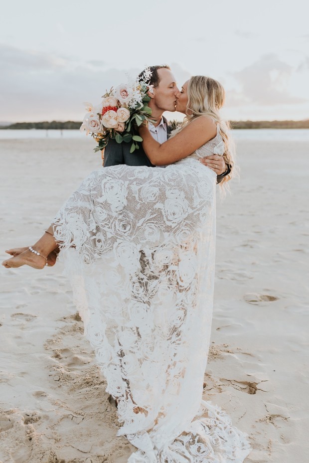 Happy couple kissing on beach after wedding, bride in dress