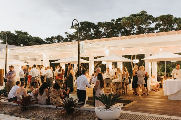 Outdoor wedding reception with string lights and a crowd of guests