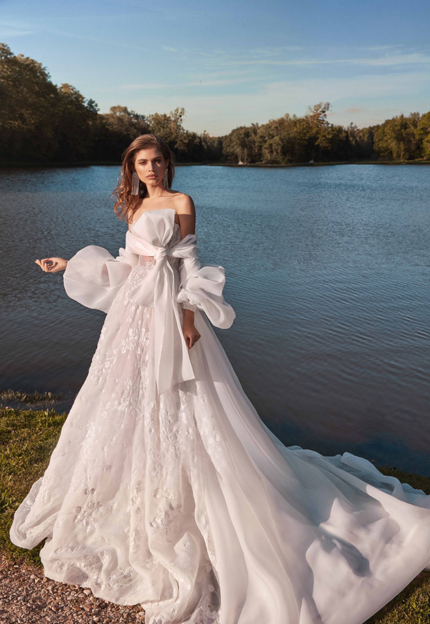 Elegant bride in a white dress posing next to a lake for a photoshoot