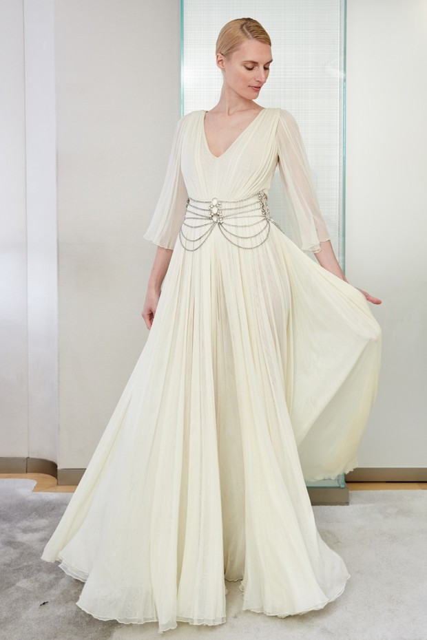 Elegant woman in a cream dress with a chain belt, flowing gown