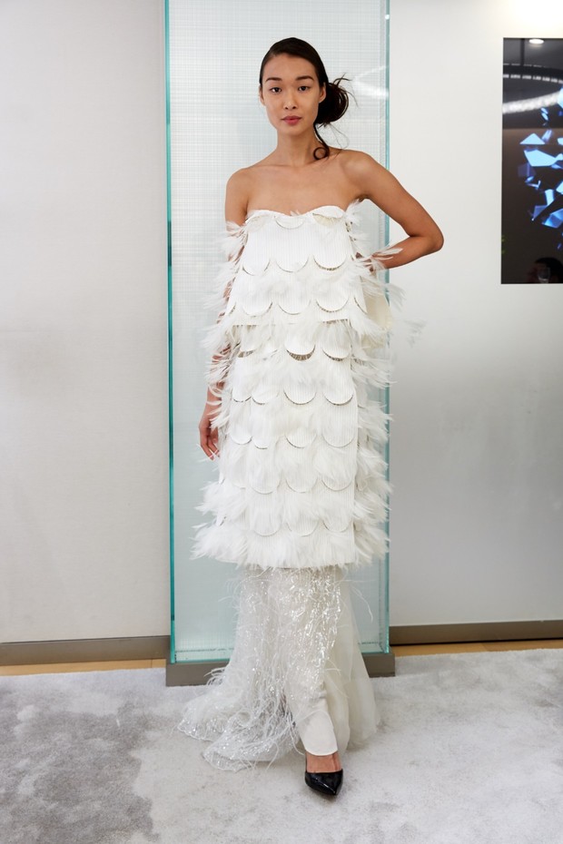 Woman in white feathery dress poses elegantly for a fashion shoot