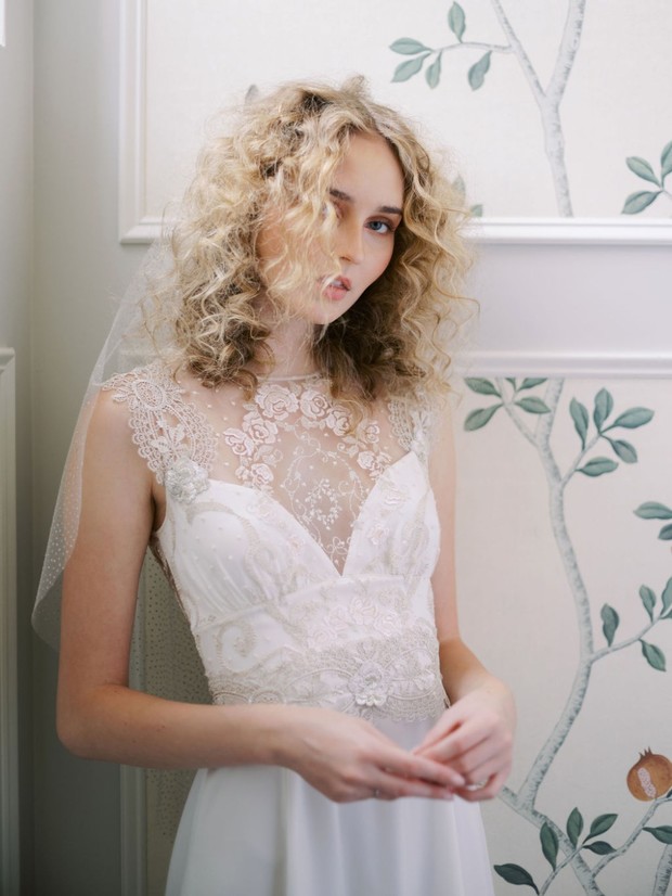 Bride in lace wedding gown with curly hair and delicate veil