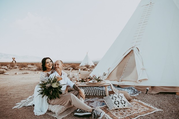Happy couple enjoying a picnic near a teepee in the desert