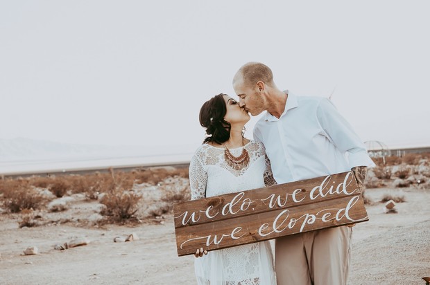 Couple eloping with we do we did we eloped sign in hand