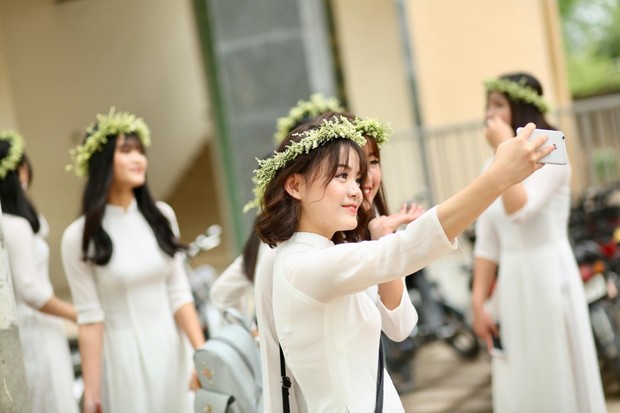 Young women in white take a selfie wearing flower crowns happily