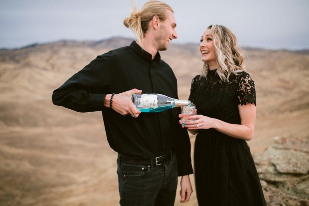 Couple celebrating outdoors with champagne in a scenic landscape
