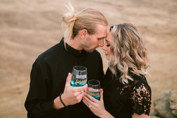 Romantic couple embraces with wine glasses marking their engagement