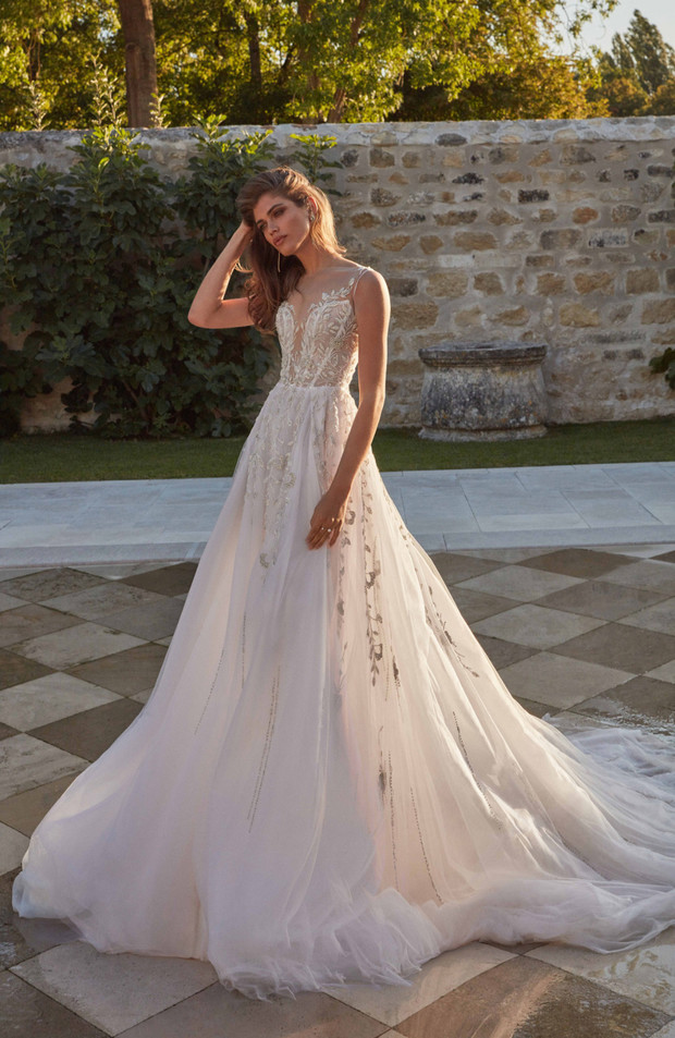 Elegant bride poses in a gorgeous flowing wedding dress outdoor