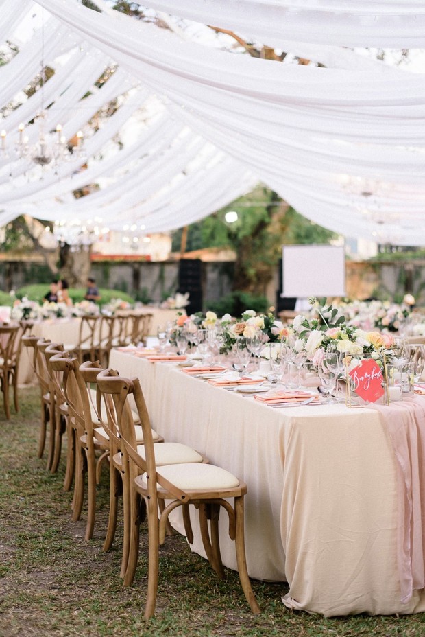 Elegant outdoor wedding reception with draped fabric decor
