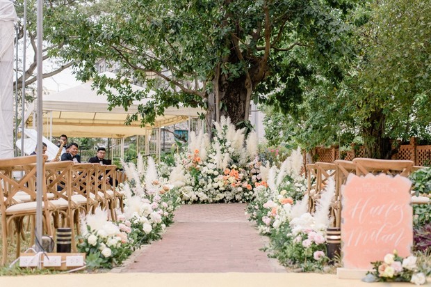 Elegant outdoor wedding ceremony with floral decor and greenery