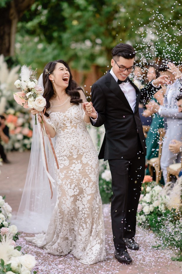 Happy newlyweds walking with confetti at an outdoor wedding