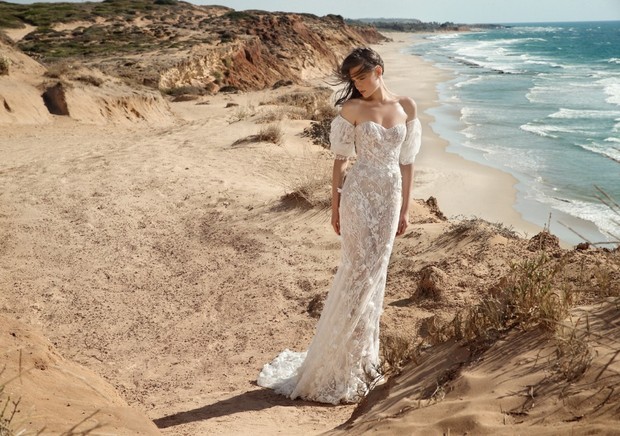 Elegant bride in a white dress on a beach with ocean and cliffs view