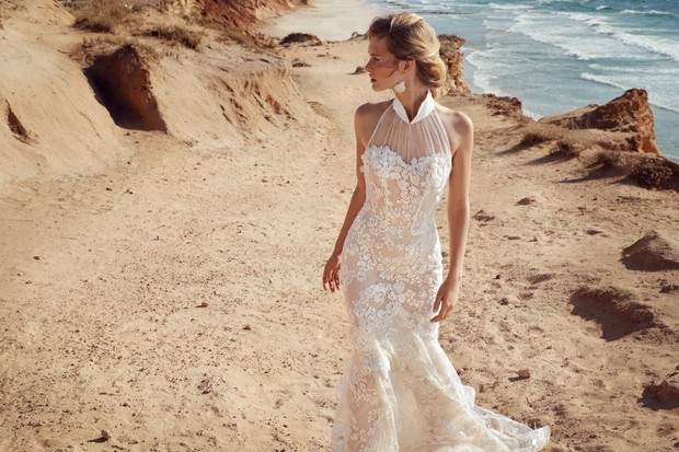 A beautiful bride in white dress on a beach with ocean in the background