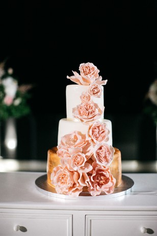 gold and white wedding cake with cascading blush roses