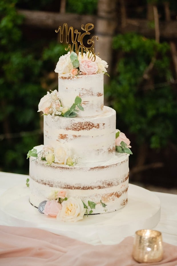 nearly naked wedding cake with blush and white flower topper