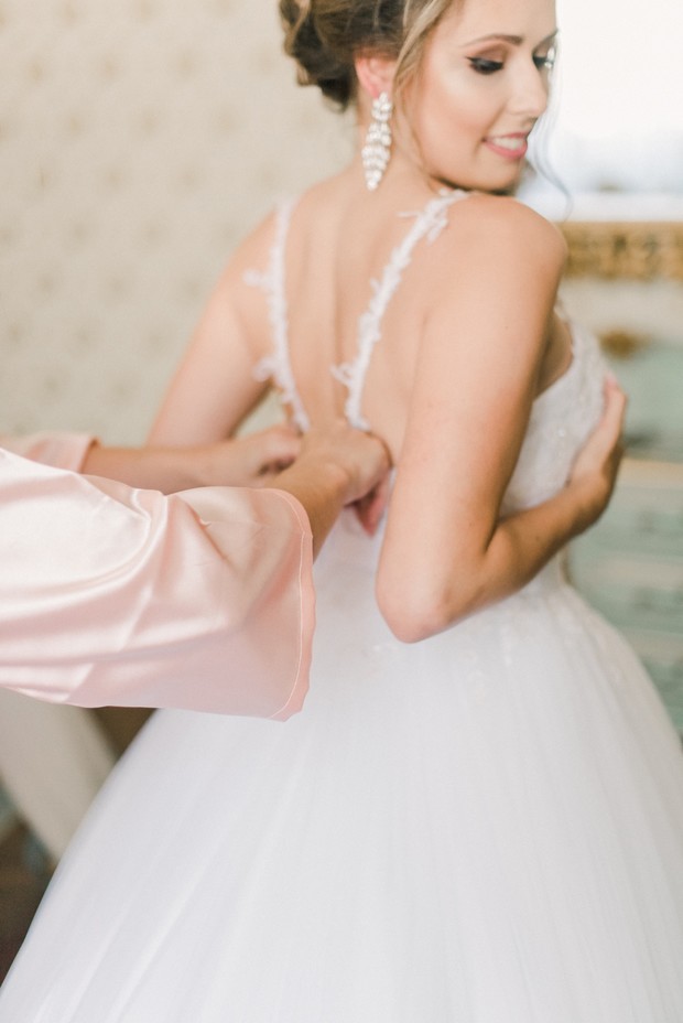 Bride getting zipped into her beautiful wedding gown