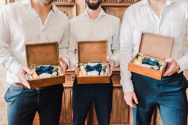 Groomsmen hold gifts in wooden boxes with bow ties