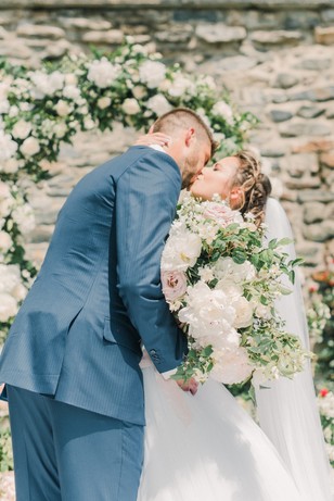 Newlyweds share a loving kiss on their wedding day surrounded by flowers