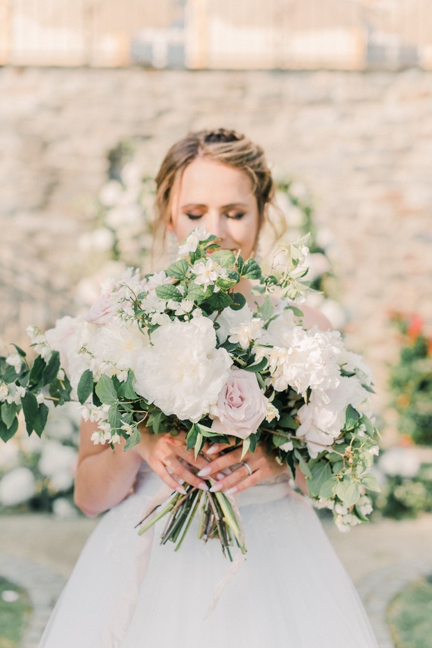 Bride holding a beautiful floral bouquet, smelling the flowers