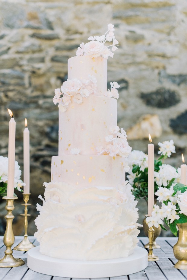 Elegant five-tiered wedding cake with floral accents and candles