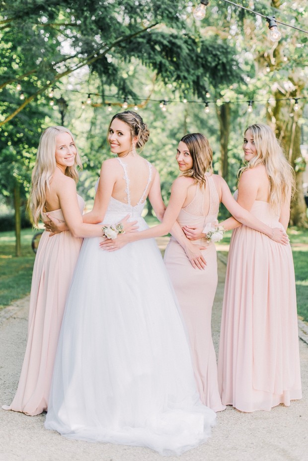 Bride and bridesmaids smiling at camera, celebrating a happy wedding day